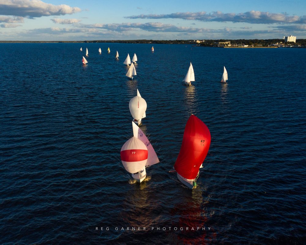 The LMSA fleet running downwind under spinnaker on Lake Monroe, with the Sanford waterfront beyond.